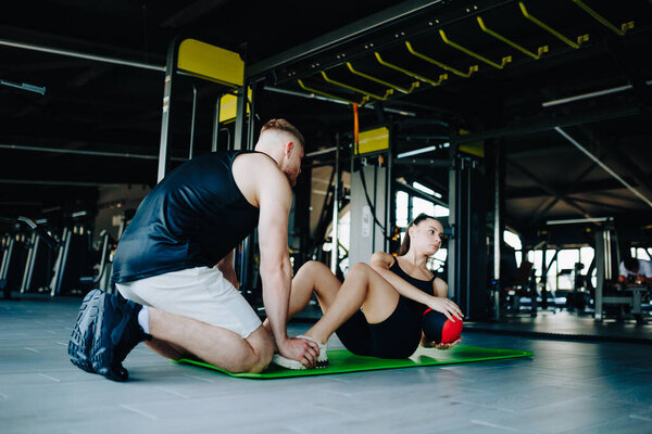 A dedicated personal trainer coaching a young woman, helping her improve her athletic abilities and overall fitness level through training with a ball.