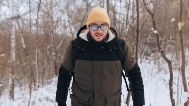 自然の中で自分自身を抱きしめ バックパックで飾られた眼鏡でコーカサス人男性として抱きしめ 雪の冒険の本質を捉え 冬のトレッキングに乗り出します — ストック動画