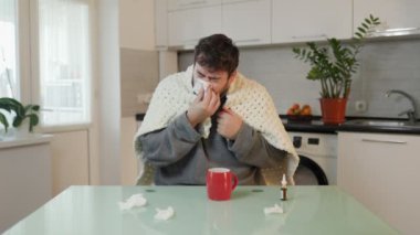 Bu fotoğrafta mevsimlik hastalıkların ayrıntılı tasviri gözler önüne seriliyor, genç beyaz bir adamı yorganın içinde, mutfak sandalyesinde titriyor ve burnunu siliyor..