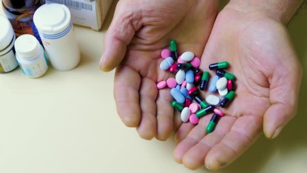 認識できない人の手の錠剤 さまざまな色の錠剤 それらの隣には薬の瓶があります 白い背景を隔離した 人々は彼の手で錠剤を保持しています — ストック動画