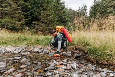 Woodland Doldurma Ritüeli Erkek Gezgini Yeşilliğin Ortasında Serinletici Bir Mola Vermek İçin Taze Su Topluyor.