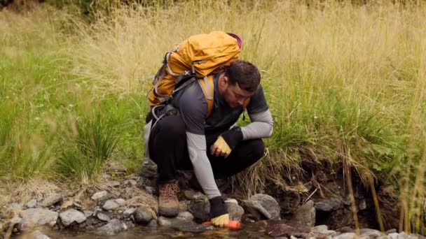 一个白人远足者拥抱了大自然 在远征的过程中从一条清澈的河里装满了他的酒壶 — 图库视频影像