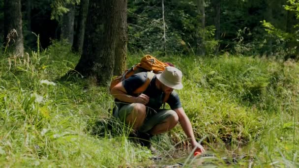 更新重新焕发生机的拉丁旅行者家伙从河里补充他的水壶 参与森林补水 — 图库视频影像
