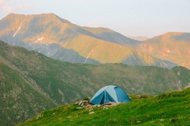 Dağların arka planında çadır. Yazın dağlarda yürüyüş çadırı. Tepelerin yukarısında kamp kuruyorlar. Hava manzaralı..