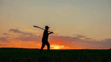 Kırsal bir akşamın huzurlu güzelliğinde, gerçek bir çiftçinin silueti ortaya çıkar, uçsuz bucaksız tarlada kürekle yürür. Dramatik gökyüzü sahneyi canlı renklerle parlatacak