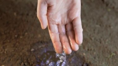 Aralarından su akarken bu çarpıcı yakın plan el ele tutuşmalar. Yumuşak su akıntısı aşağıdaki toprakla temas ettiğinde rahatlatıcı ve sakinleştirici bir etki yaratır.