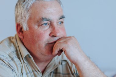 Ağırlaştırılmış Duygular. Sakallı bir yaşlının yakın plan görüntüleri. Ciddi bir yüz ifadesi. Ev ortamının yalnızlığını ve üzüntüsünü yöneten yaşlı bir erkeğin mücadelesini ve hayal kırıklığını gösteriyor..