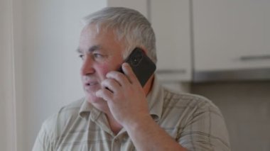 Dijital Diyaloglar Bu resim, evde akıllı telefonuyla sohbet eden olgun bir dedeyi yakalar ve yaşlıların modern iletişim araçlarına ne kadar kolay uyum sağladıklarını gösterir..