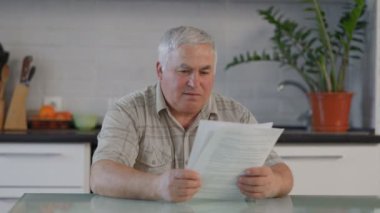Mutfağında işten çıkarma mektubu okuyan üzgün bir emeklinin gerçekçi tasviri. Hayal kırıklığı ve finansal belirsizliğin hakiki duygularını yakalıyor..