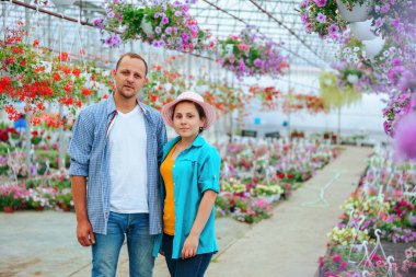 Hevesli bir çiçek satıcısı ailesi bir serada duruyor, sonra dönüp kameraya bakıyor. Çift mutlu, yüzlerinde muzaffer bir gülümsemeyle. Boşluğu kopyala