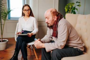 Genç kadın psikolog, acemi uzman koltukta oturan ihtiyarı dikkatle dinler. Zihinsel bozukluklar her zaman tedavi edilemez. yaşlanma, zihinsel bozukluklar.