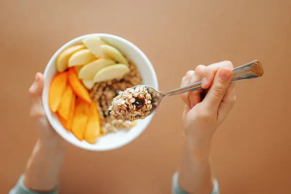 Stock image Close up spoon with granola in female hand unrecognizable. Nearby pieces of raw fruit and dried fruit. The concept of healthy food and diet. easy and delicious.