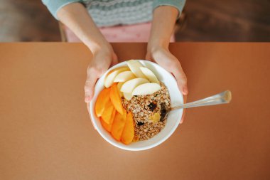 Manzara çiğ yulaf, mango doğal kase ve kaşık kadınların elinde. Sağlıklı vejetaryen kahvaltı kasesi elleri dişi, meyveler, tahıl yakın. Vegan, vejetaryen, temiz yemek, diyet, kilo verme konsepti