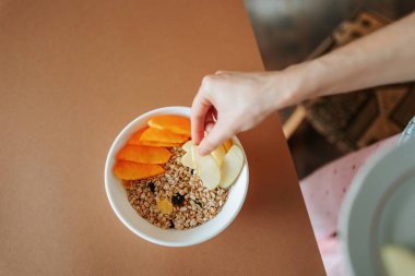 Masada bir tabak müsli ve meyve yenmeyi bekliyor. Bir kadın ana yemekle birlikte meyve istifler. Sağlıklı beslenme ve beslenme konsepti. Bütün aile yulaf ezmesi yer..