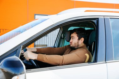 Tuhaf bir genç adam arabada oturur ve direksiyona sıkıca tutunur. Adam aylaklık ediyor ve keyfi yerinde..