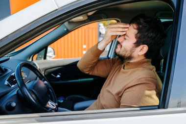 Genç sakallı adamın başı ağrıyor. Kafasını elinde tutuyor ve arabada. Acı çeken ve mutsuz olan bir erkek, insanlar acı çekiyor, çaresiz insanlar, o hasta, acı çekiyor.