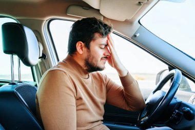 Migren ve baş ağrısı, direksiyonda oturan genç bir adama büyük işkence ediyor. Şoför sağlık sorunları nedeniyle çok üzgün. Sakal..