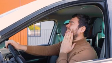 İspanyol sakallı şoför direksiyonda dişleri ağrıyan ve acı çeken adam delirmiş. Güzel, genç adam negatif duygulara sahip diş ağrısı, yüzünde eli var.