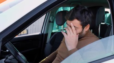 Genç sakallı adamın başı ağrıyor. Kafasını elinde tutuyor ve arabada. Acı çeken ve mutsuz olan bir erkek, insanlar acı çekiyor, çaresiz insanlar, o hasta, acı çekiyor.