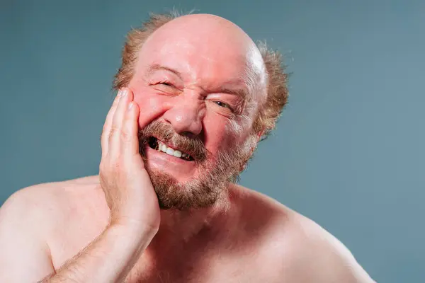 stock image Front view upset unhappy elderly man holding his cheek screaming from toothache moustache bald gray hair. A concept suffering from toothache. Studio isolated blue background.