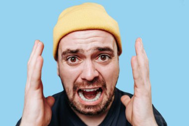 Bir adamın çığlık atarken çekilmiş yakın bir portre görüntüsü, deliliğin ve çaresizliğin ifadesi doğrudan kameraya bakıyor ve öfkeyle haykırıyor..