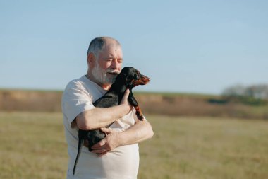 Gün batımında, kıdemli bir beyefendi sadık daksundusu ile saf bir mutluluk anını paylaşıyor, yürek ısıtan bir sahne yaratıyor..