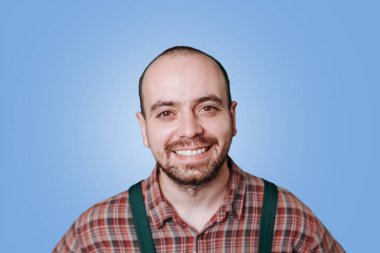 Parlak ve neşeli bir portre, mutlu sakallı bir işçinin bir stüdyo çekimindeki neşesini yakalar. Bu genç profesyonel, tulumları ve şık sakallarıyla pozitiflik ve memnuniyet sergiliyor..