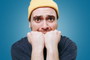 Bir insanın portresini yakından çek, içlerinden biri bir adam, kameraya doğrudan baktıklarında negatif bir duyguya kapılmış. Mavi arkaplanda stüdyo çekimi,