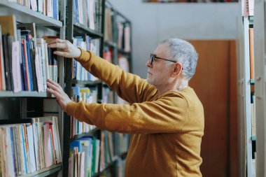 Kütüphanede Kitap Arayan Sakallı ve Gözlüklü Yaşlı Bir Adamın Portresi