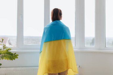 Bir dikiz aynası, Ukrayna bayrağını gururla taşıyan ve vatanseverliğini vurgulayan bir kadını evinin penceresinin yanında yakalar..