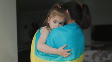 Kapalı alanda yakalanan bir anne ve çocuk, Ukrayna bayrağına sarılmış bir şekilde birbirlerinin kollarında teselli ve güç buluyorlar..