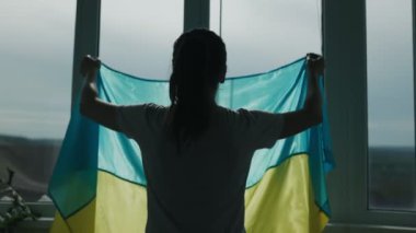 Bir dikiz aynası, Ukrayna bayrağını gururla taşıyan ve vatanseverliğini vurgulayan bir kadını evinin penceresinin yanında yakalar..