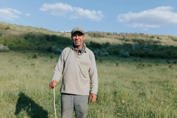 Stock image the dignified presence of a senior peasant man farmer, his weathered face telling the story of a lifetime spent working the land and tending to his flock in the natural beauty of the countryside.