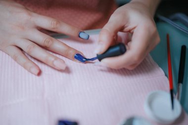 Kişisel bakım ve kişisel bakım kavramı, titizlikle bir parmağa oje sürerek, bir manikür seansı sırasında uzman bir manikürcünün uzmanlığını gözler önüne sererek yaklaştı..