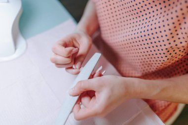 Tereddüt etmeden, manikürcü bir kadın özen ve kişisel bakım özünü somutlaştırmak için evde tırnakları üzerinde titizlikle çalışır..