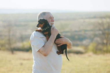 Gün sona ererken, yaşlı bir adam ve evcil dachshund gün batımında tarlanın huzurunu kucaklıyor..