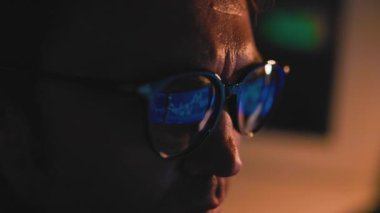 Gece Kuşu Ticareti Bir erkek tüccar, tamamen dijital ticaret ve yatırım dünyasına dalmış. Yüzünün yakın çekimi çalışkan ve kararlı doğasını gözler önüne seriyor.