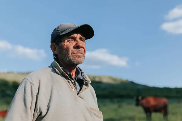 stock image Against the backdrop of the rural landscape, this portrait encapsulates of an elderly peasant man farmer, his hat and weathered features speaking volumes about his life and work outdoors.