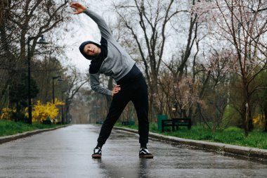 Atletik hüner. Kendine güvenen genç bir atlet. Açık havada jimnastik yaparak akrobatik becerilerini ve fiziksel yeteneklerini sergiliyor..