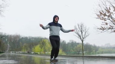 Yağmurlu bir günde erkek sporcu ip atlama açık havada. Yağmura rağmen, bu adam kendini tamamen fiziksel eğitimine adamış. Zorlu ve etkili bir egzersiz seansı için ip atlıyor..