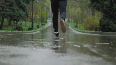 Kararlı bir sporcu yoğun bir antrenman sırasında yağmurda koşar, odaklanmış ifadesi ve güçlü adımları sarsılmaz bağlılığını gösterir.