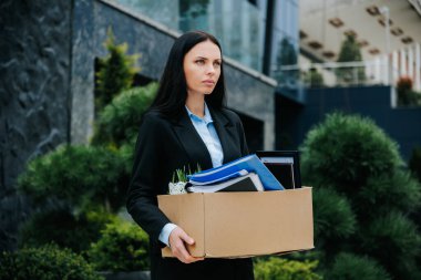 A woman standing outside with a box, a symbol of the loss of her job and work. Empty Handed Woman Outside with Loss of Job and Work clipart