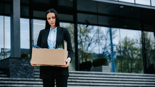 Job Loss and Unemployment Taking a Toll. A worker holds a cardboard box, their expression reflecting the stress of losing their job due to the recession and job loss.