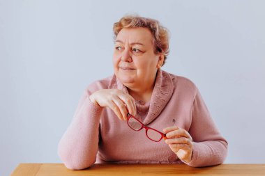 Evde Gözlüklü Kıdemli Kadın, evde kilolu yaşlı bir kadın, dayanıklılığını ve iç güzelliğini kutlayan çarpıcı bir portrede yakalandı..