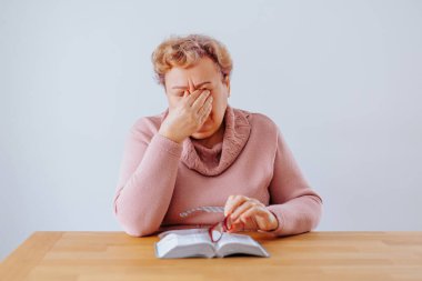 Kitap okurken kendini üzgün ve bitkin hisseden kilolu yaşlı kadın. Son sınıf öğrencisi bir kadın evde kitap okuyor, gözlüğü burnuna tünemiş. Düşüncelere dalmış gibi görünüyor ama stres çizgileri...