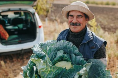 Sürdürülebilir tarım uygulamalarına kendini adamış kıdemli bir tarım uzmanının resmedildiği görsel bir yolculuğa çıkın. Bu resimde, uzman çiftçi gururla sunar: