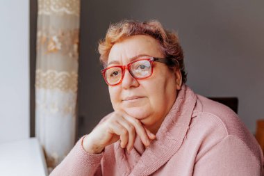 Otantik Yaşlı Kadın Portresi, evde güzel yaşlı bir kadın, gözlüğü ışıkta parıldarken portresi için gülümsüyor..