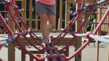 Mutlu küçük bir kız, oyun parkındaki ip merdivene tırmanır. Maceracı ruhu, keşfettiği her yeni basamağa ulaştığında kıkırdamaları çınlar..