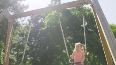 Sevimli küçük bir kız oyun parkından aşağı kayıyor, dibe inerken kıkırdaması yankılanıyor, heyecanını tekrar tırmanmak için acele ederken gösteriyor..