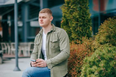 Yakışıklı bir İspanyol bir şehirde cep telefonunu kontrol ediyor. Akıllı telefonlu hoş bir genç adam şehir hayatından zevk alıyor.